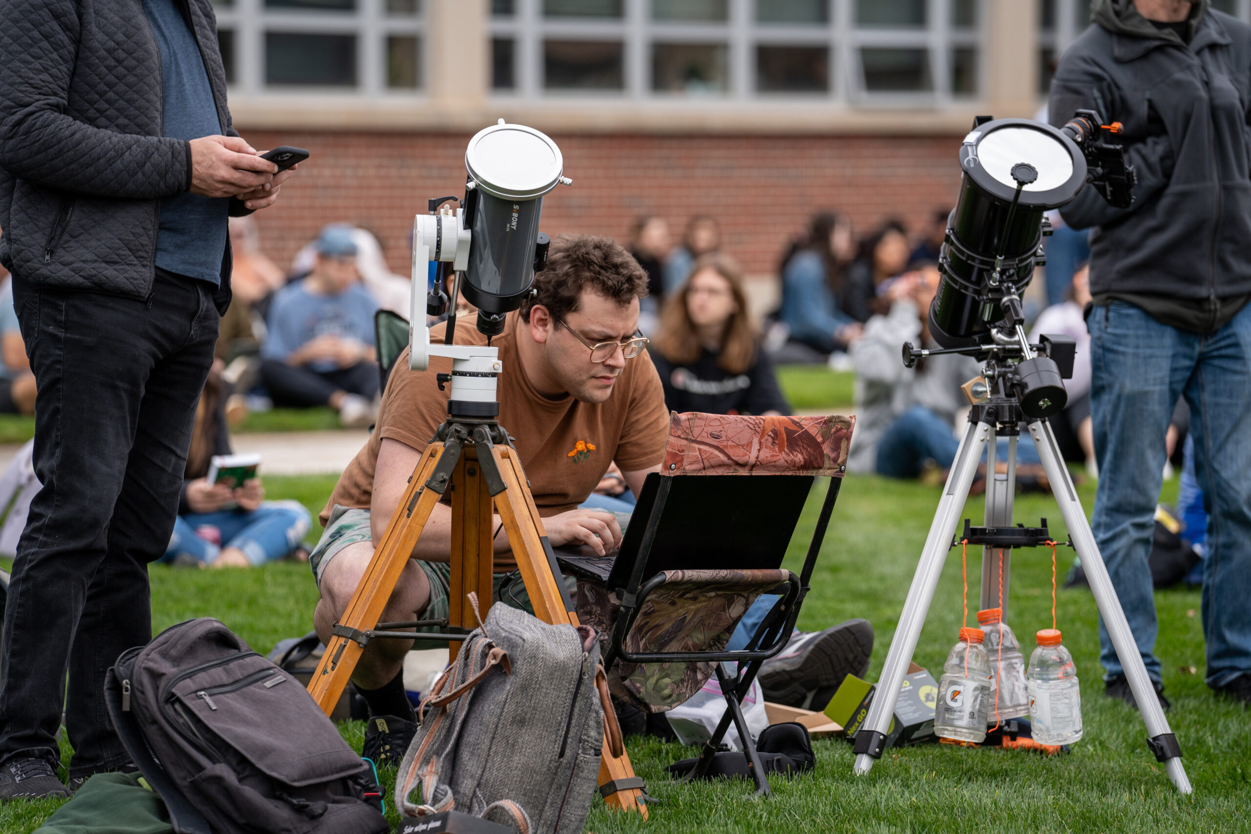 Noah Goldstein hunches over his laptop outside, fine-tuning his equipment for eclipse observation. He was one of many spectators with telescopes on the Quad. 