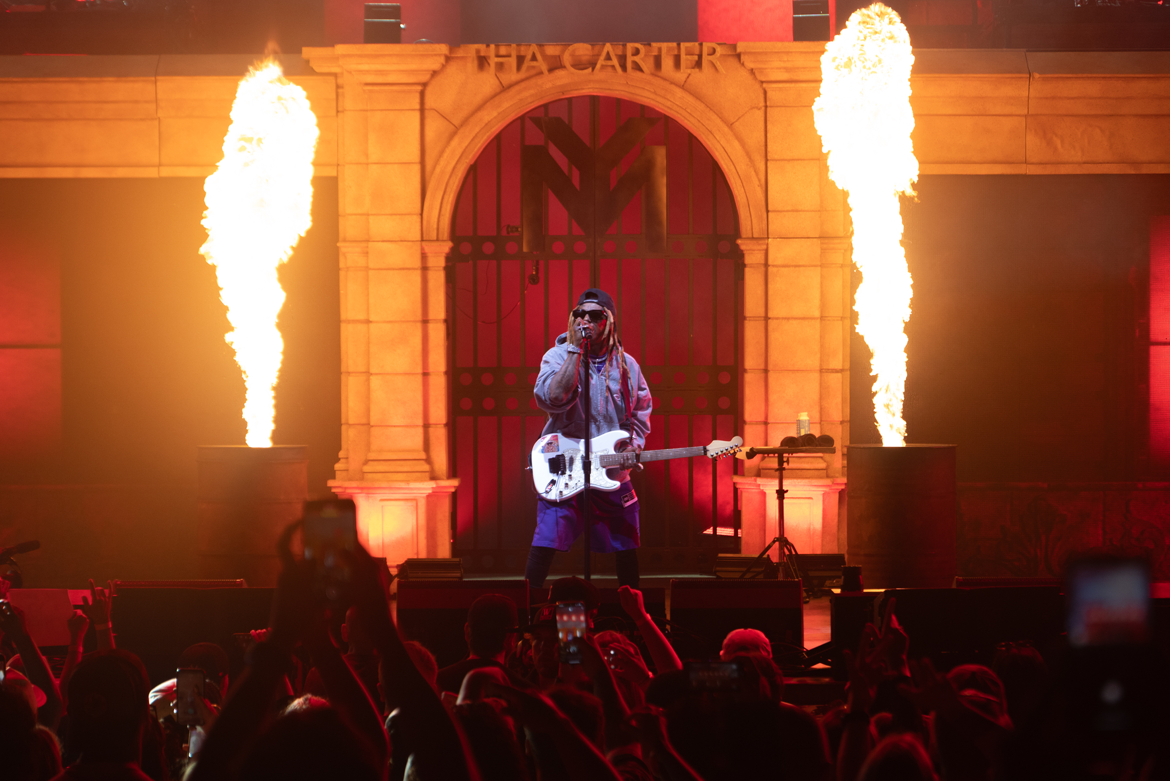 Fire erupts from behind Lil Wayne as the crowd roars to his rap lyrics. 