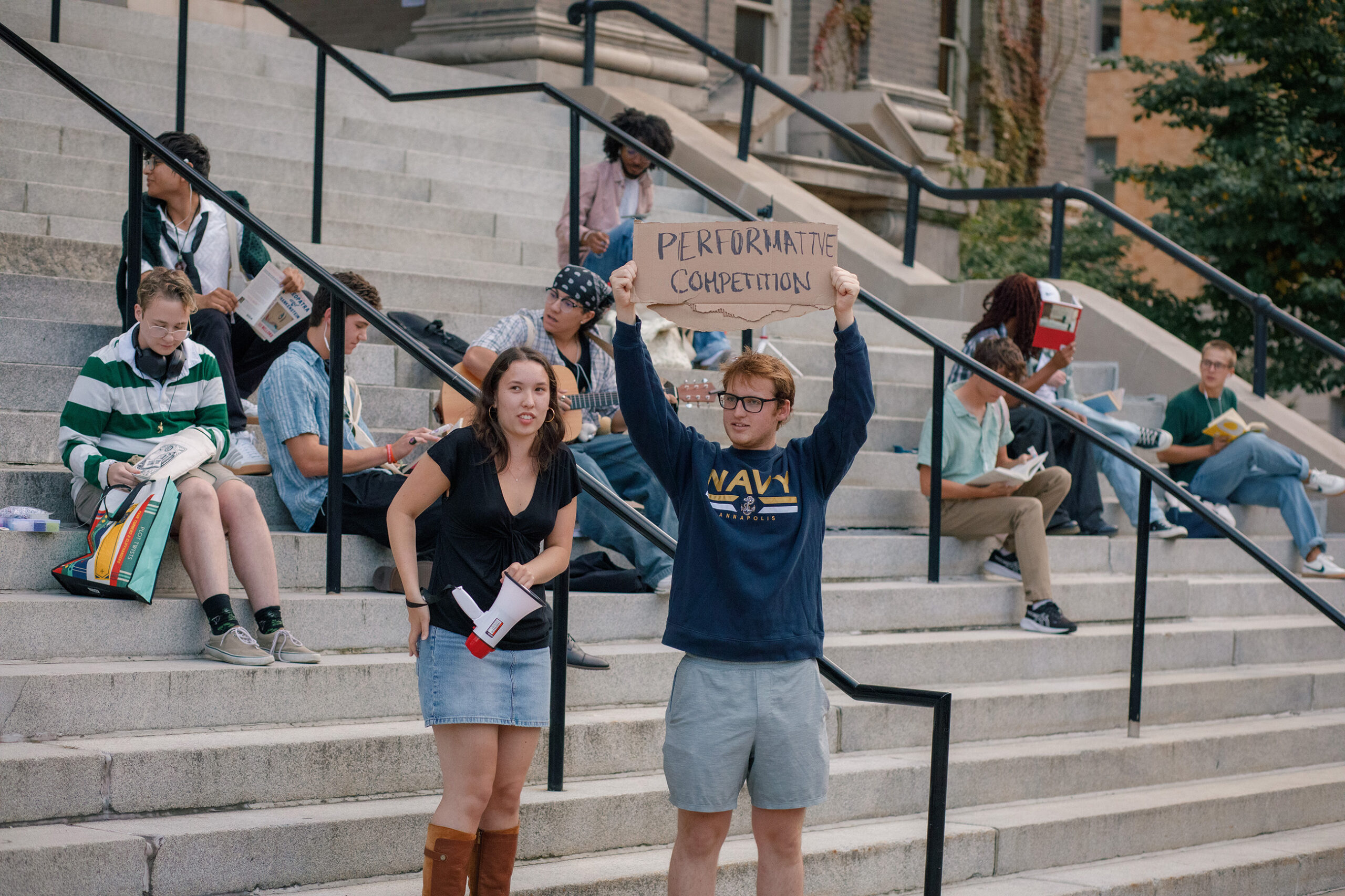 The host, Jordan Burda, stands next to someone gathering all the performative males to the Carnegie steps. Burda moderated the event starting with an introduction round, followed by a question response round and finally a speech round.