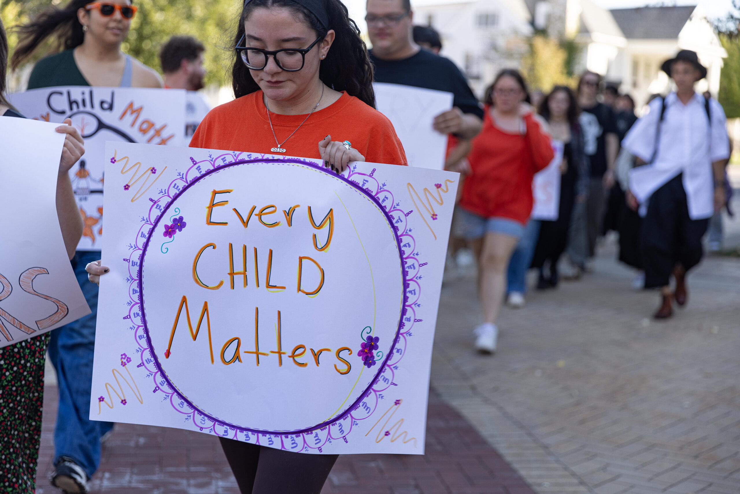 Demonstrators walk with posters that say “Every child matters,” each designed differently. The materials were hand-drawn prior to the event.