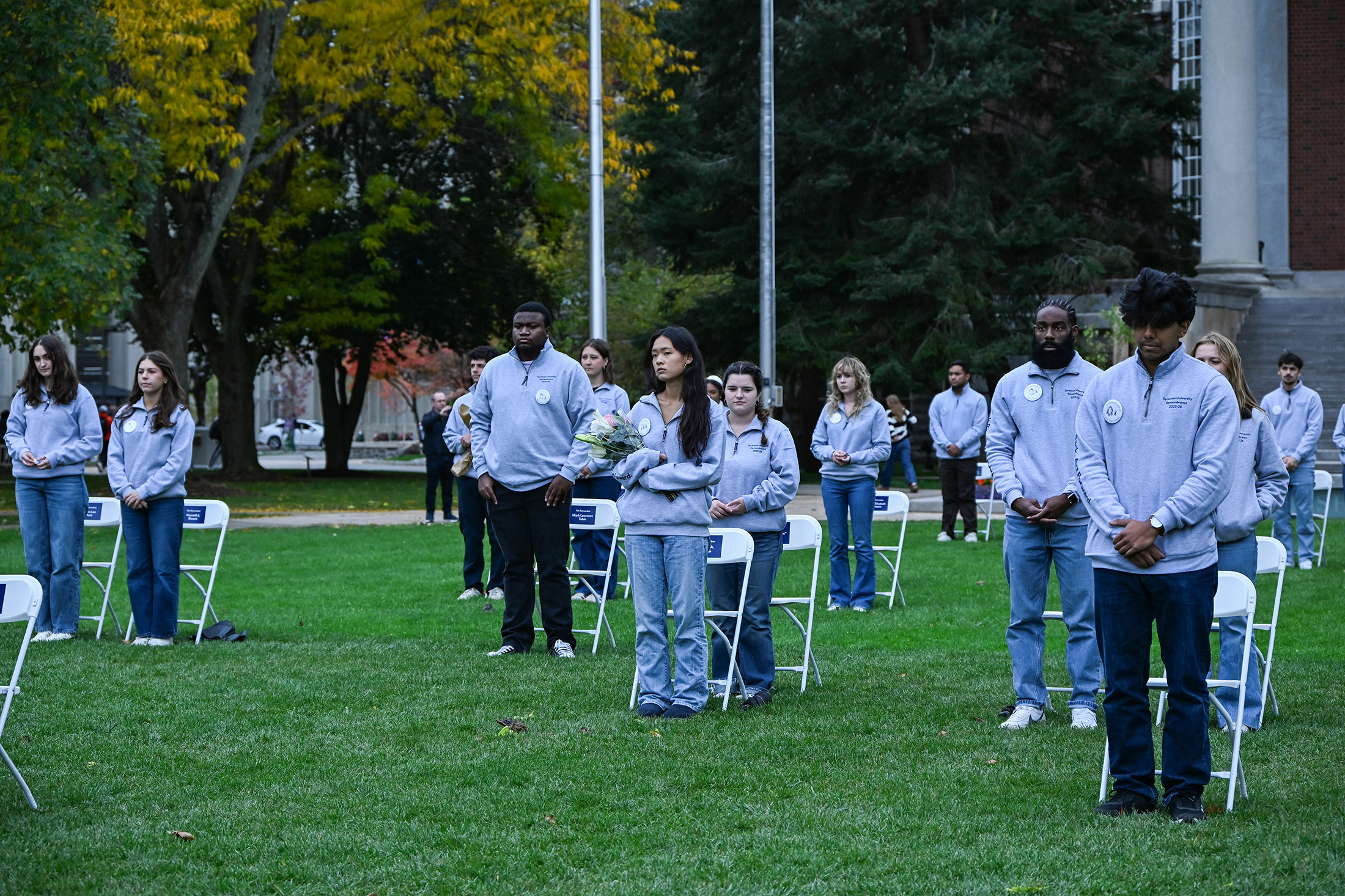 Remembrance Scholars stand silently to begin the annual “Sitting in Solidarity” ceremony on the Shaw Quadrangle. The Wednesday afternoon ceremony lasted 35 minutes to represent the 35 Syracuse University students who died in the bombing.