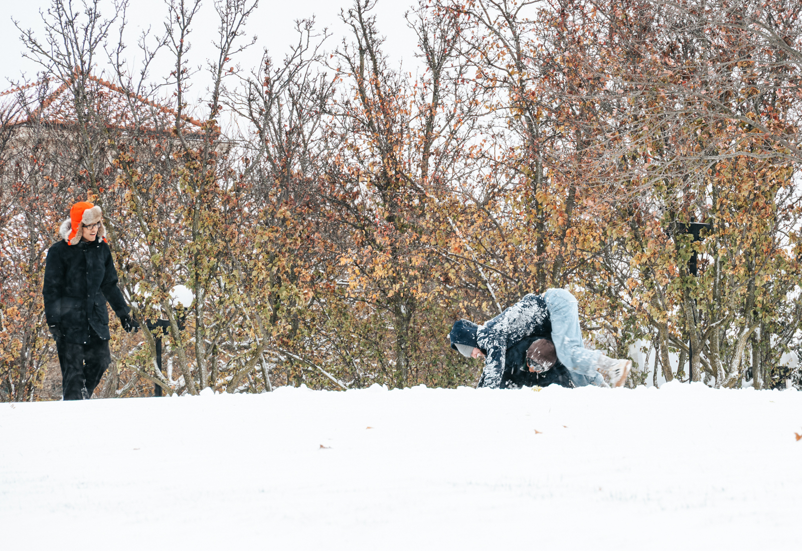 Students playfully roll around in the snow in front of the Hall of Languages as the season’s first snow transforms campus into a winter playground.