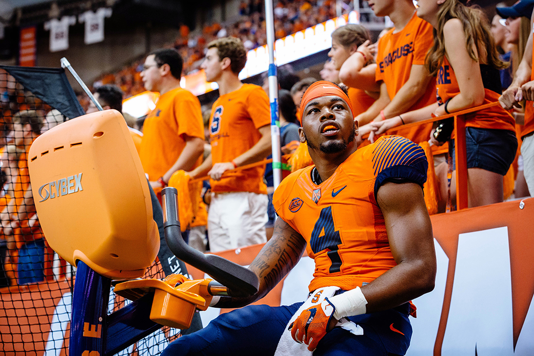Runningback Dontae Strickland watches the defense from the big screen as he warms up in the sidelines.