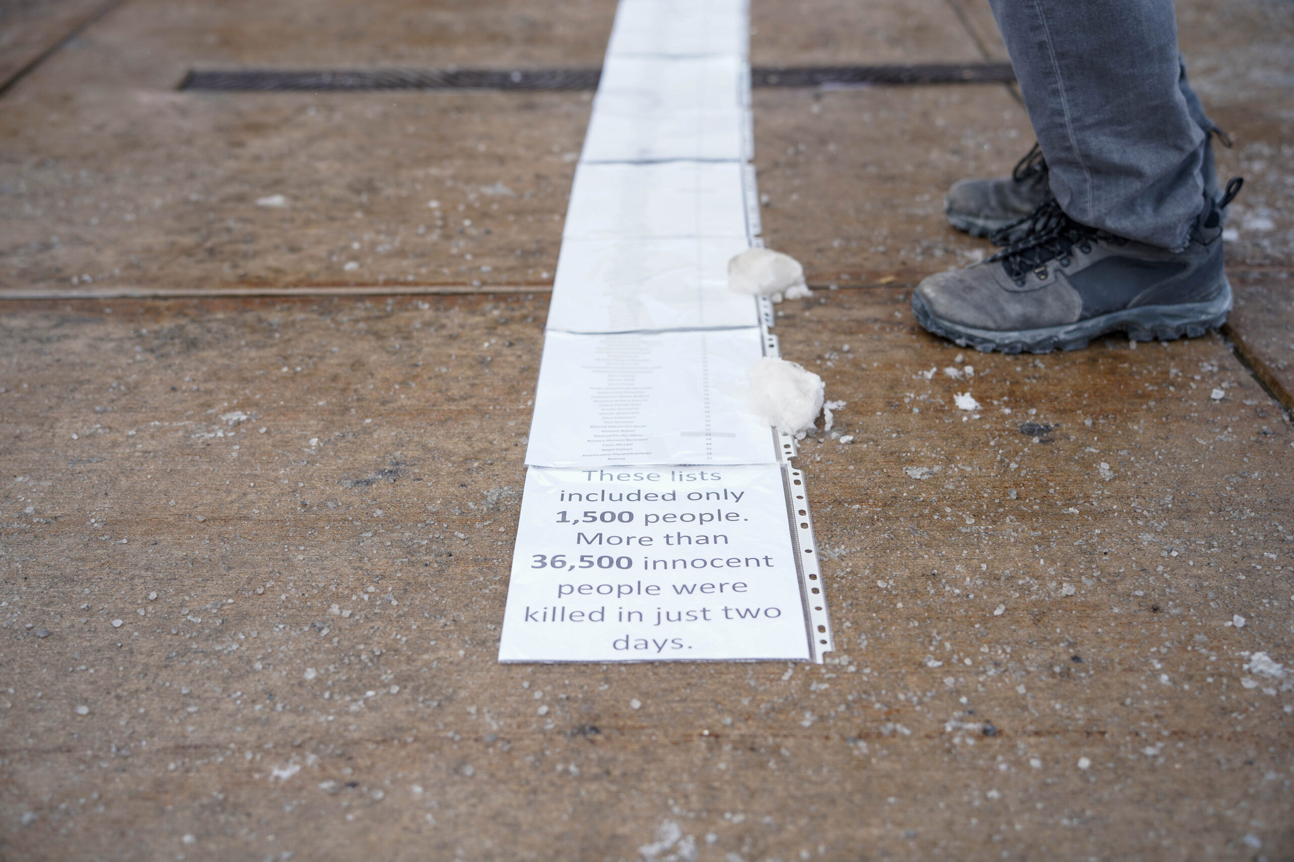 Pieces of paper line the sidewalk containing names listed in the Iranian government's death toll.