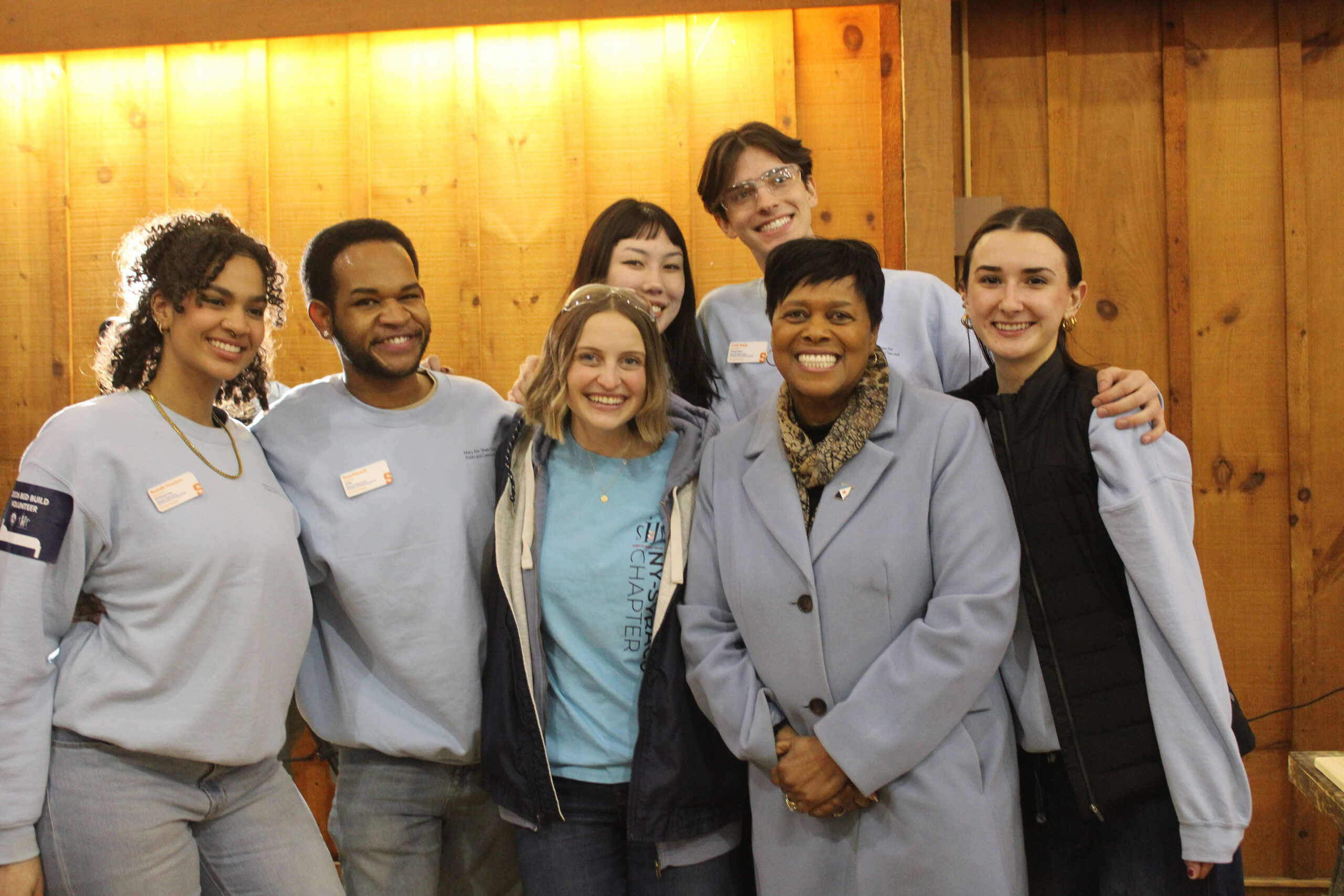 Seven people stand, smiling at the camera.