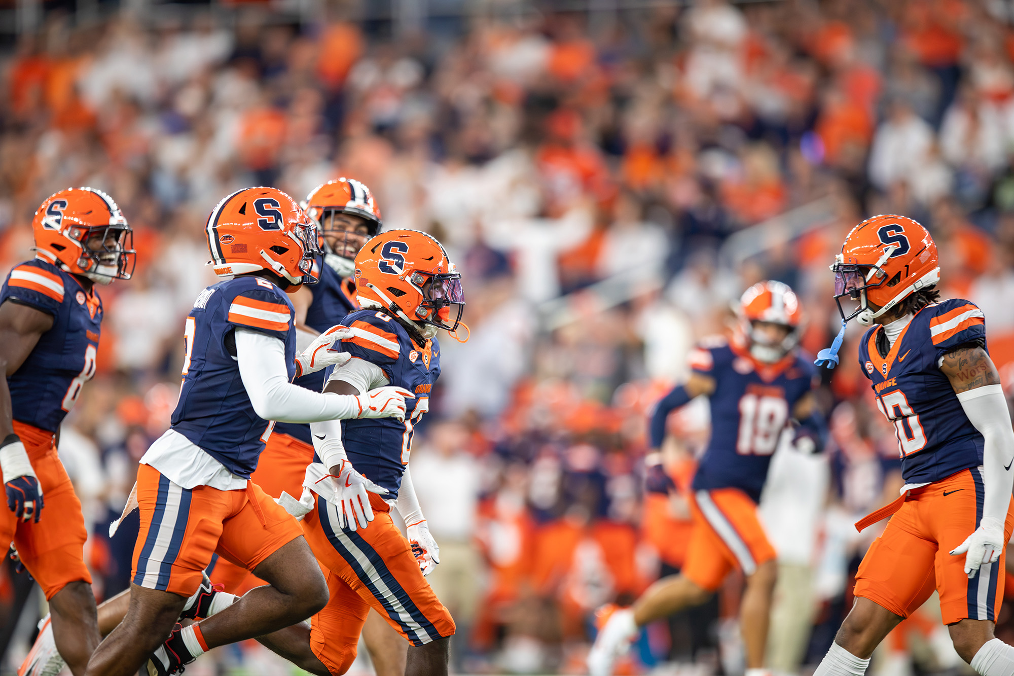Photo of Syracuse football players celebrating on the field during a home game
